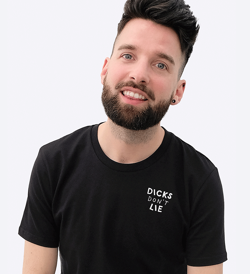 Roger Huskens (a cute guy with a beard, dark hair, blue eyes and chest hair) is smiling into the camera wearing a black logo shirt from Dicks Don't Lie.